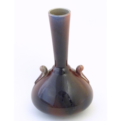 141 - An Arts & Crafts Linthorpe style flambe bottle vase with a flared rim and styled twin handles. Impre... 