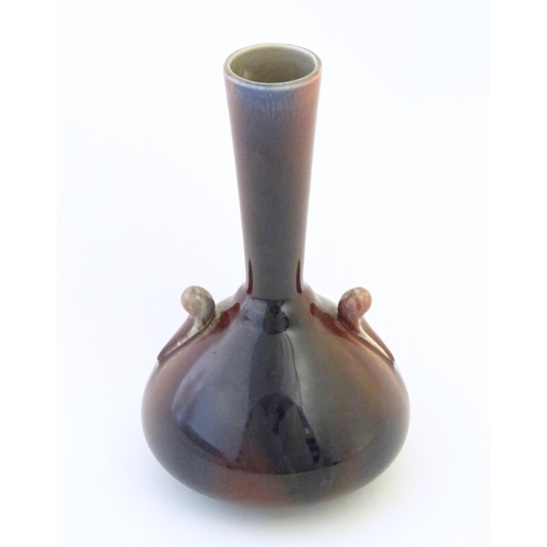 141 - An Arts & Crafts Linthorpe style flambe bottle vase with a flared rim and styled twin handles. Impre... 