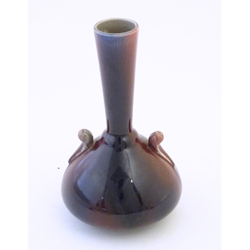 141 - An Arts & Crafts Linthorpe style flambe bottle vase with a flared rim and styled twin handles. Impre... 