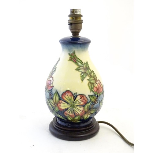 142 - A Moorcroft style lamp base with tube lined decoration depicting flowers and foliate. Approx. 10 3/4... 