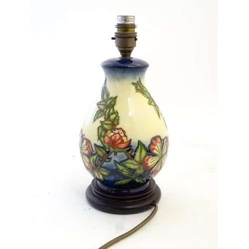 142 - A Moorcroft style lamp base with tube lined decoration depicting flowers and foliate. Approx. 10 3/4... 