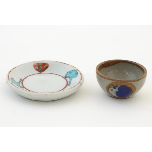 112 - A small saucer with naive hand painted decoration, together with a small tea bowl decorated with the... 