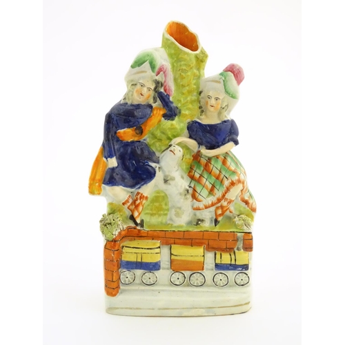 62 - A Victorian Staffordshire pottery bud vase with two children in highland dress with a dog between th... 