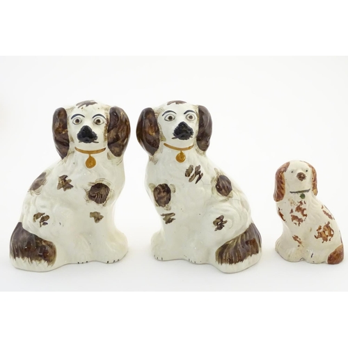 62A - A pair of Staffordshire pottery seated spaniels, together with another smaller example. Largest appr... 