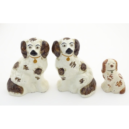 62A - A pair of Staffordshire pottery seated spaniels, together with another smaller example. Largest appr... 