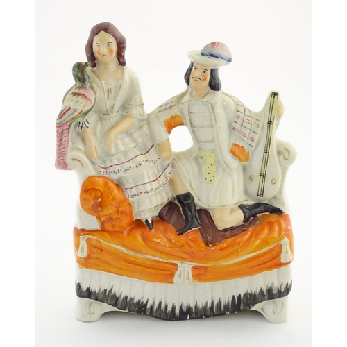 65 - A Staffordshire flatback figural group of a man with a musical instrument and a woman with a parrot,... 