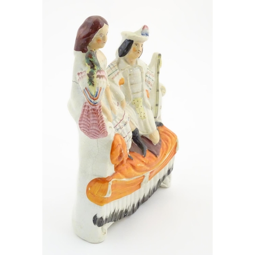 65 - A Staffordshire flatback figural group of a man with a musical instrument and a woman with a parrot,... 