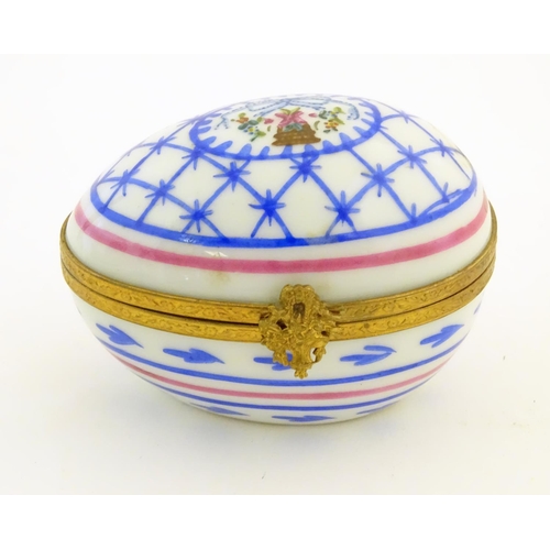 92 - A Limoges hand painted trinket box of egg form with bell and floral detail. Marked under. Approx. 1 ... 