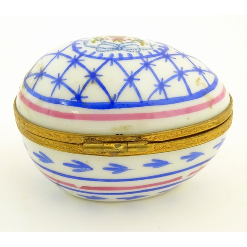 92 - A Limoges hand painted trinket box of egg form with bell and floral detail. Marked under. Approx. 1 ... 