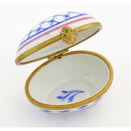 92 - A Limoges hand painted trinket box of egg form with bell and floral detail. Marked under. Approx. 1 ... 