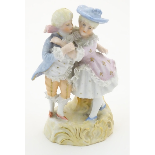 95 - A Continental figural group depicting a man and woman in 18thC dress with porcelain lace detail and ... 