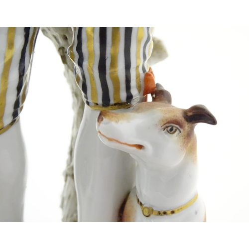 97 - Two German porcelain figures, a model of a young man holding a hat and flower with a dog beside him,... 