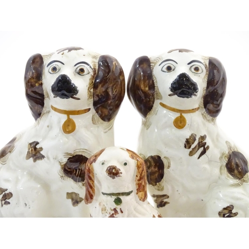 62A - A pair of Staffordshire pottery seated spaniels, together with another smaller example. Largest appr... 