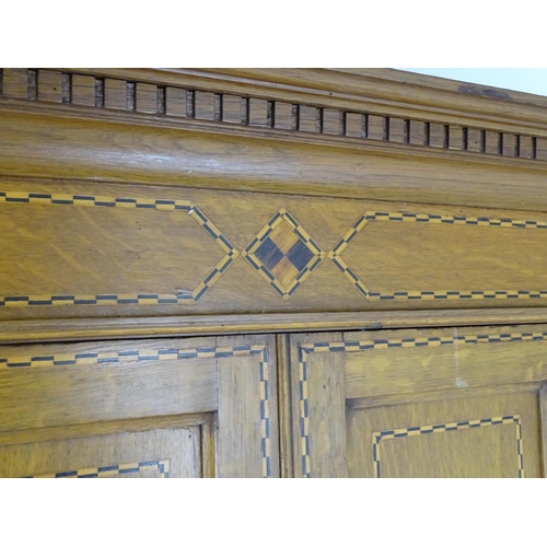 1469 - An early / mid 20thC oak triple wardrobe, having a moulded dentil carved cornice above a checkered i... 