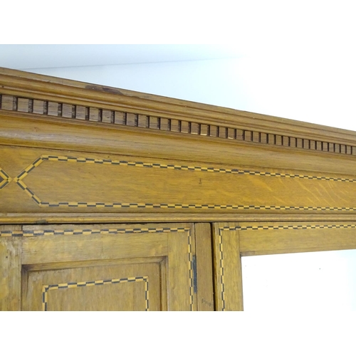 1469 - An early / mid 20thC oak triple wardrobe, having a moulded dentil carved cornice above a checkered i... 