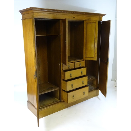 1469 - An early / mid 20thC oak triple wardrobe, having a moulded dentil carved cornice above a checkered i... 