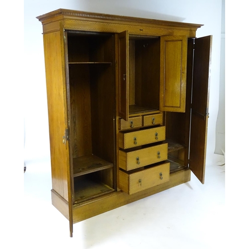 1469 - An early / mid 20thC oak triple wardrobe, having a moulded dentil carved cornice above a checkered i... 