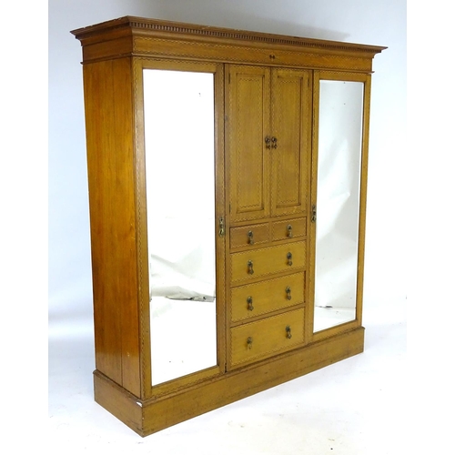 1469 - An early / mid 20thC oak triple wardrobe, having a moulded dentil carved cornice above a checkered i... 