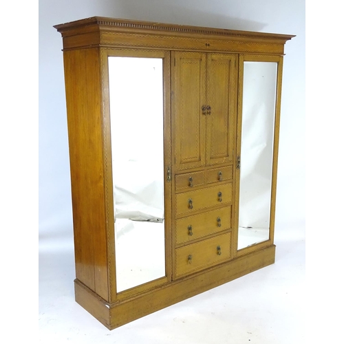 1469 - An early / mid 20thC oak triple wardrobe, having a moulded dentil carved cornice above a checkered i... 