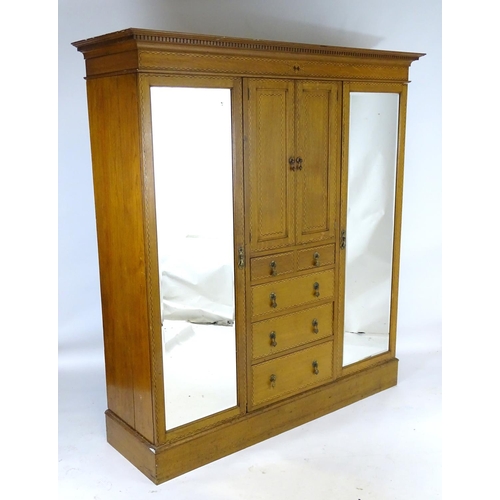 1469 - An early / mid 20thC oak triple wardrobe, having a moulded dentil carved cornice above a checkered i... 
