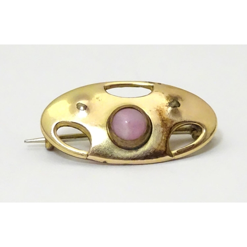 924 - An Arts & Crafts gilt metal brooch set with pink stone cabochon. Marked to reverse with monogram for... 