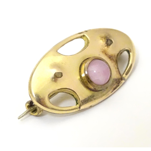 924 - An Arts & Crafts gilt metal brooch set with pink stone cabochon. Marked to reverse with monogram for... 