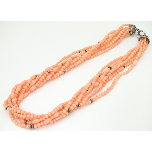 941 - A 7-strand necklace of pink coral coloured beads with silver clasp. Approx 18