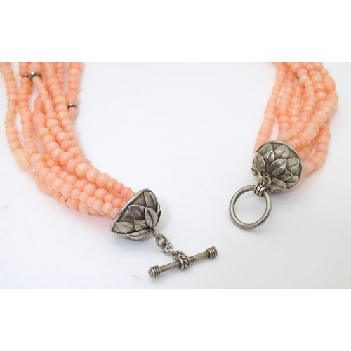 941 - A 7-strand necklace of pink coral coloured beads with silver clasp. Approx 18