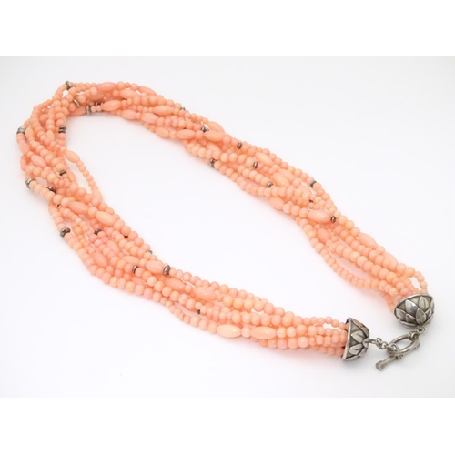 941 - A 7-strand necklace of pink coral coloured beads with silver clasp. Approx 18