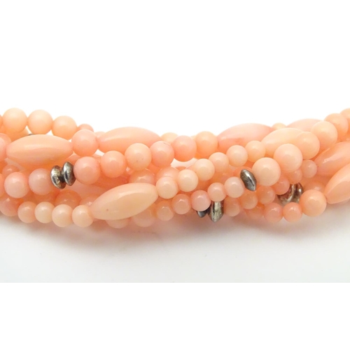 941 - A 7-strand necklace of pink coral coloured beads with silver clasp. Approx 18