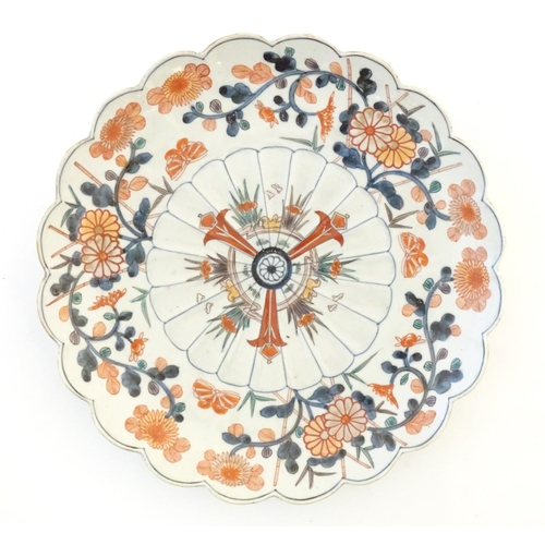 57 - An Oriental plate with a scalloped rim decorated in the Imari palette with floral and foliate detail... 