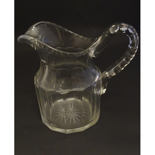 262 - A large 19thC glass water jug , decorated with fluted oval and roundel cuts, with starburst to the b... 