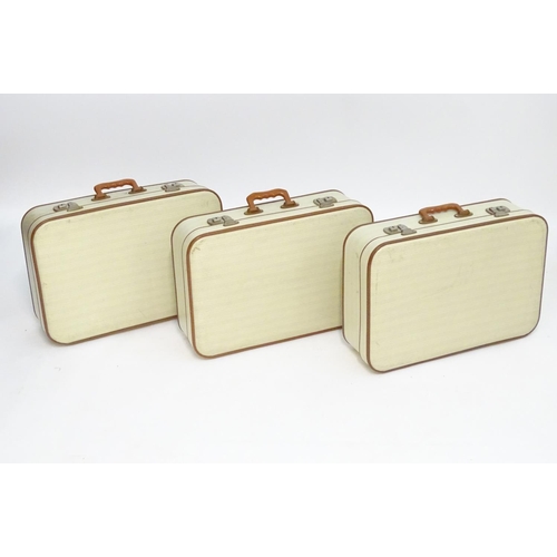 1341 - A mid 20thC set of three travelling suitcases by Cheney, London, in white with tan trim, each with d... 