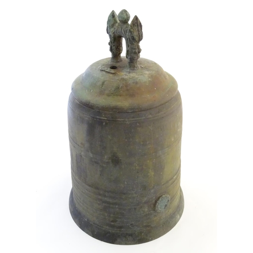 1345 - An Oriental cast temple bell the handle with twin mask detail. Approx. 19 1/4