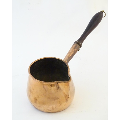 1366 - A 19thC copper saucepan with spout and turned wooden handle. Approx. 14 1/4