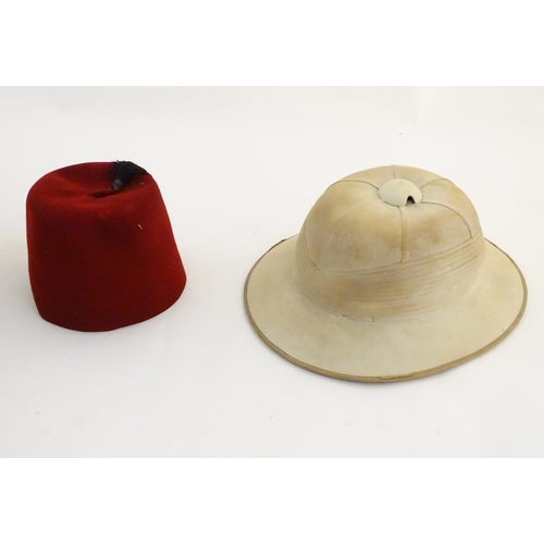 1558 - A 20thC Christy's London pith helmet for the Tropics, labelled within. Together with a fez, both con... 