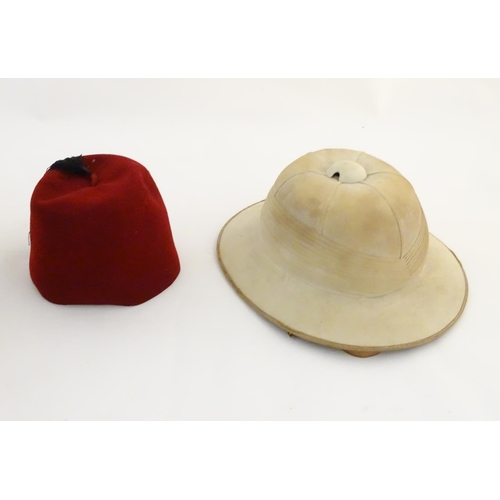 1558 - A 20thC Christy's London pith helmet for the Tropics, labelled within. Together with a fez, both con... 