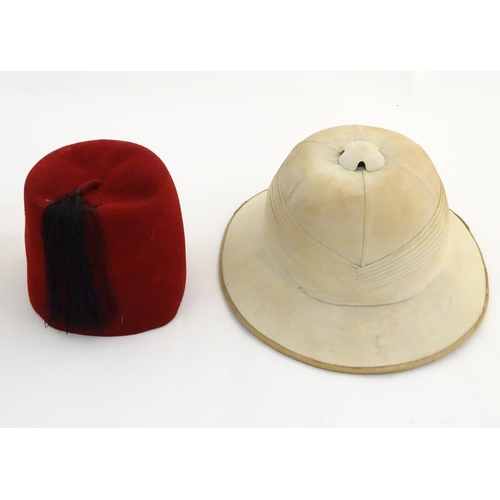 1558 - A 20thC Christy's London pith helmet for the Tropics, labelled within. Together with a fez, both con... 