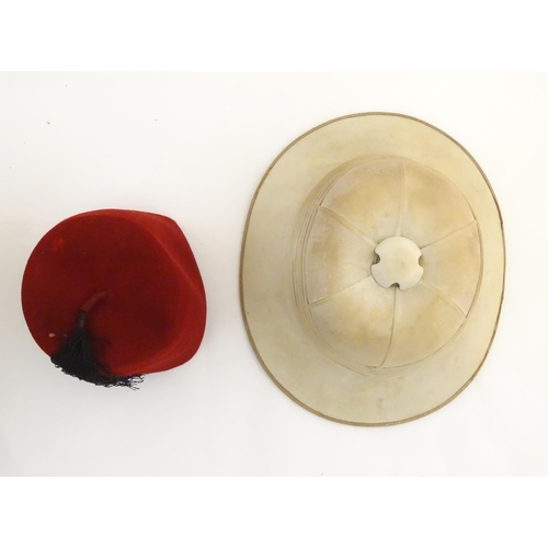 1558 - A 20thC Christy's London pith helmet for the Tropics, labelled within. Together with a fez, both con... 