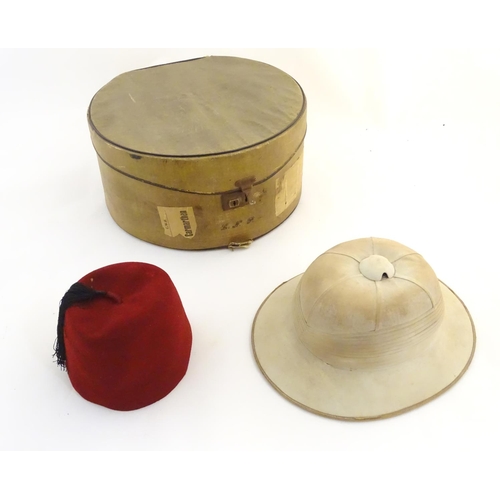 1558 - A 20thC Christy's London pith helmet for the Tropics, labelled within. Together with a fez, both con... 