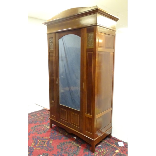 2093 - An early 20thC mahogany wardrobe with a bowed pediment above a moulded cornice and decoratively stru... 