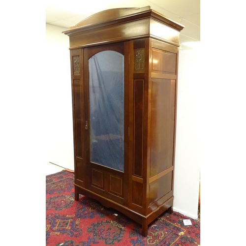 2093 - An early 20thC mahogany wardrobe with a bowed pediment above a moulded cornice and decoratively stru... 