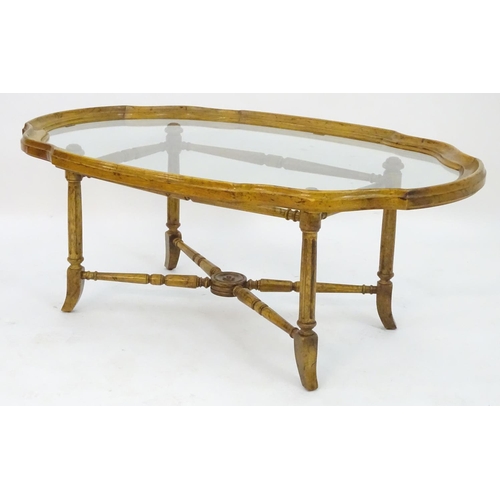 2214 - A mid to late 20thC occasional table, the base with x stretcher supporting a framed glass top, 44 1/... 