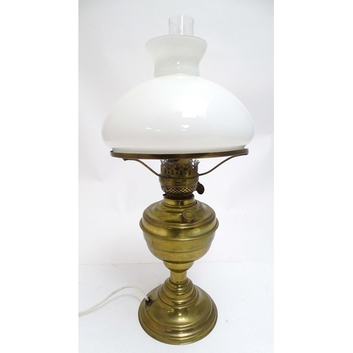 2256 - An early 20thC brass oil lamp, converted to electricity, the lobed body supporting a milk glass shad... 