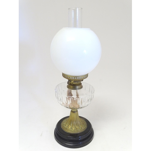 2259 - An early 20thC oil table lamp, the white globular glass shade supported by a clear cut glass reservo... 