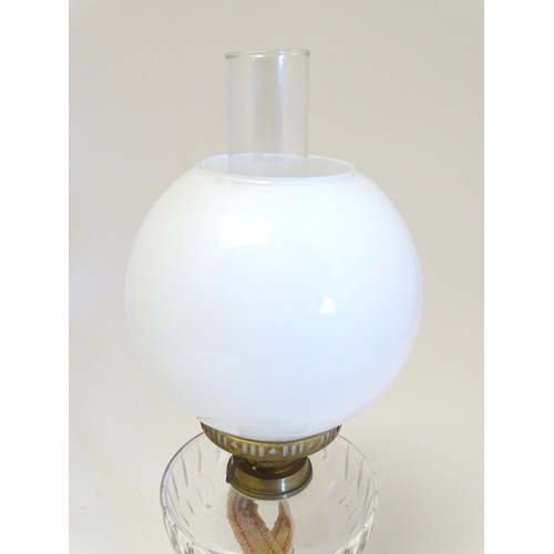 2259 - An early 20thC oil table lamp, the white globular glass shade supported by a clear cut glass reservo... 