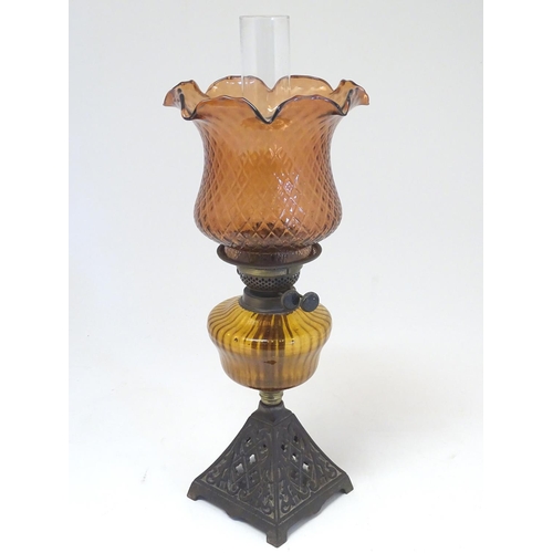 2265 - A late 19thC Duplex oil lamp, with bronzed glass shade and reservoir, standing on a cast iron base w... 