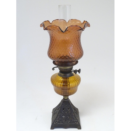 2265 - A late 19thC Duplex oil lamp, with bronzed glass shade and reservoir, standing on a cast iron base w... 