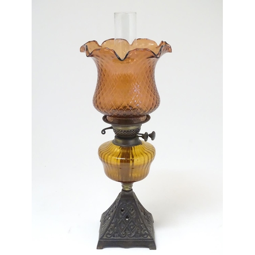 2265 - A late 19thC Duplex oil lamp, with bronzed glass shade and reservoir, standing on a cast iron base w... 