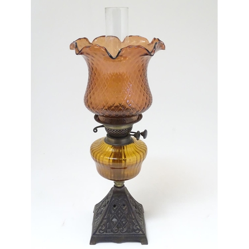 2265 - A late 19thC Duplex oil lamp, with bronzed glass shade and reservoir, standing on a cast iron base w... 